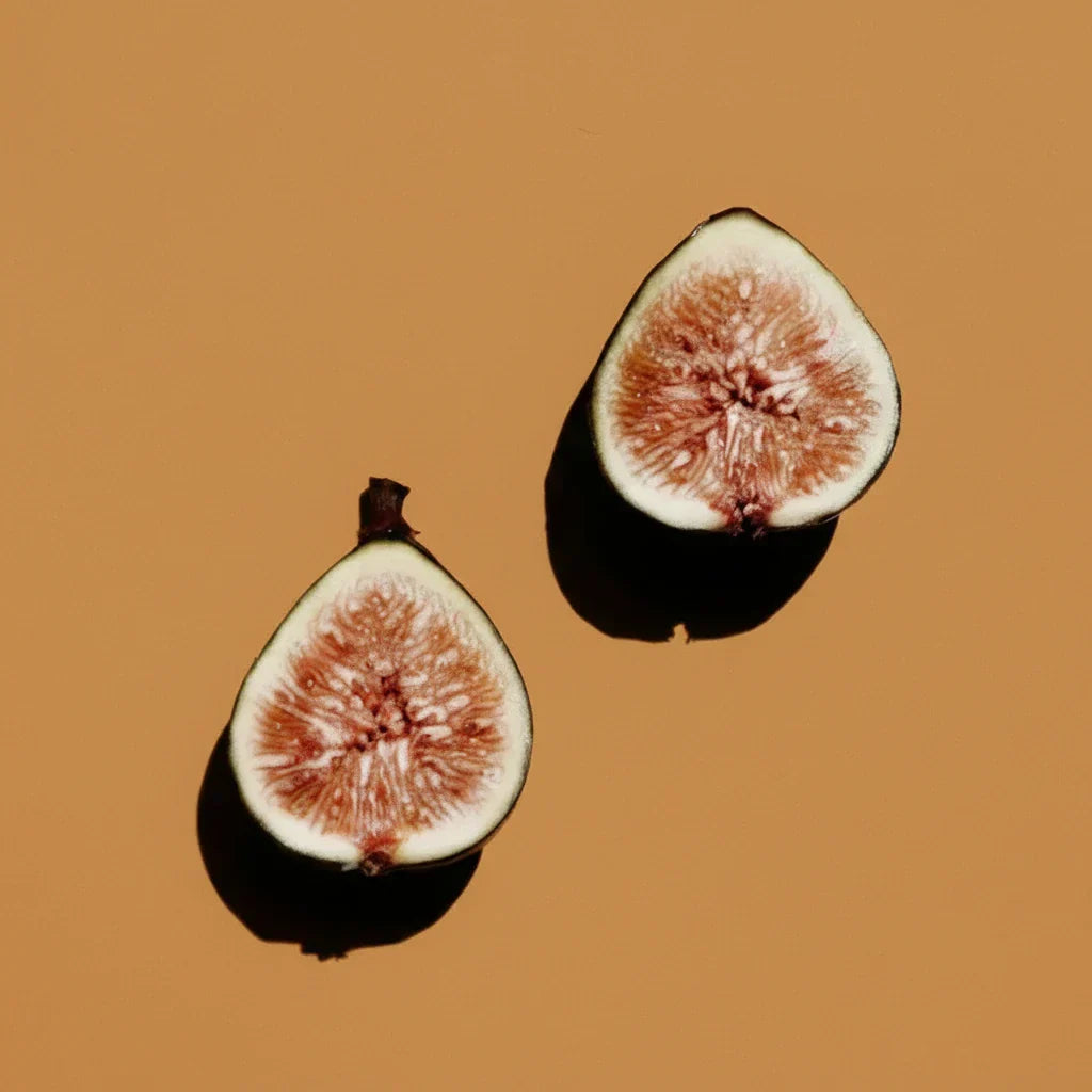 Two halves of a fresh fig on an orange background — fig fragrance note spotlight