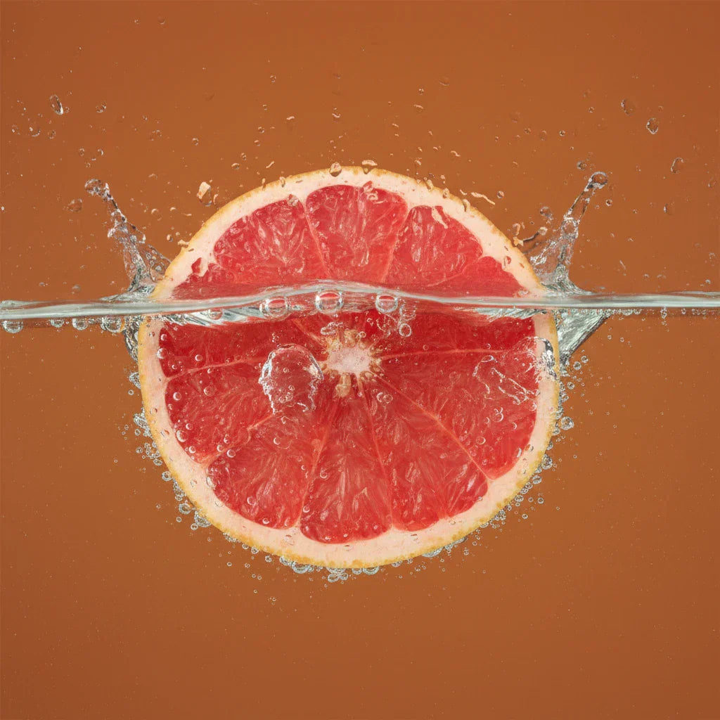 Grapefruit submerged underwater on an orange background — grapefruit fragrance note spotlight