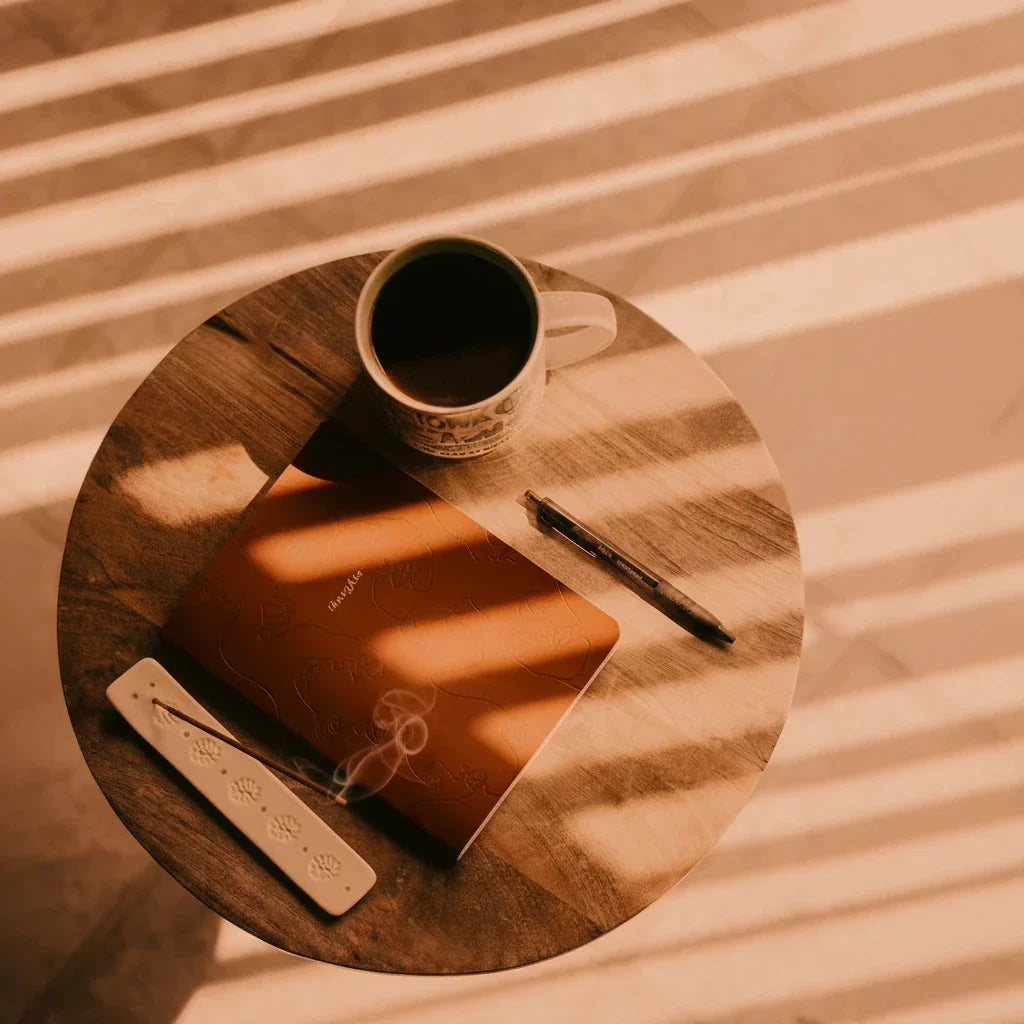A warm flat-lay scene featuring a handmade journal on an orange surface, evoking mindful writing and holistic wellness practice.
