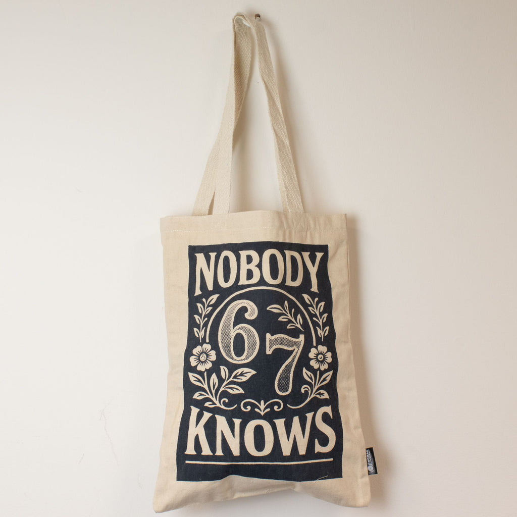 Beige tote bag with 'Nobody Knows 6 7' text on a white background