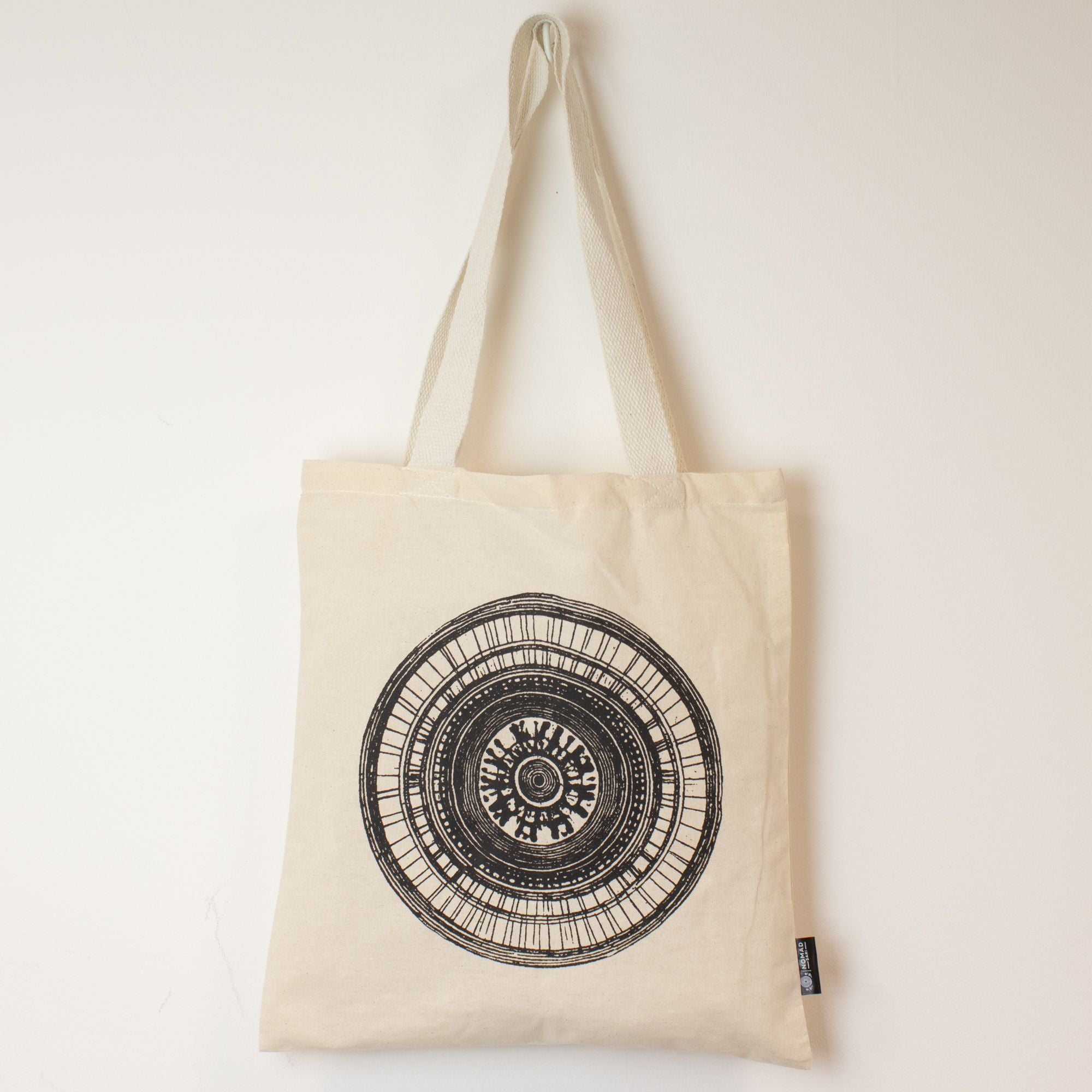 Beige tote bag with black circular design on a white background