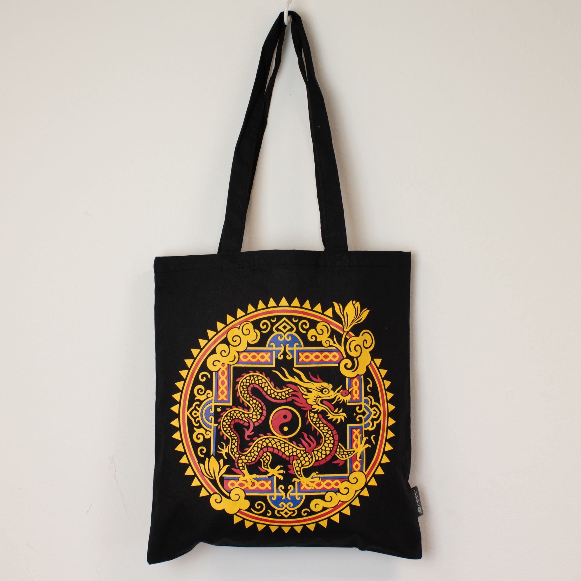 Black tote bag with a colorful dragon design on a white background