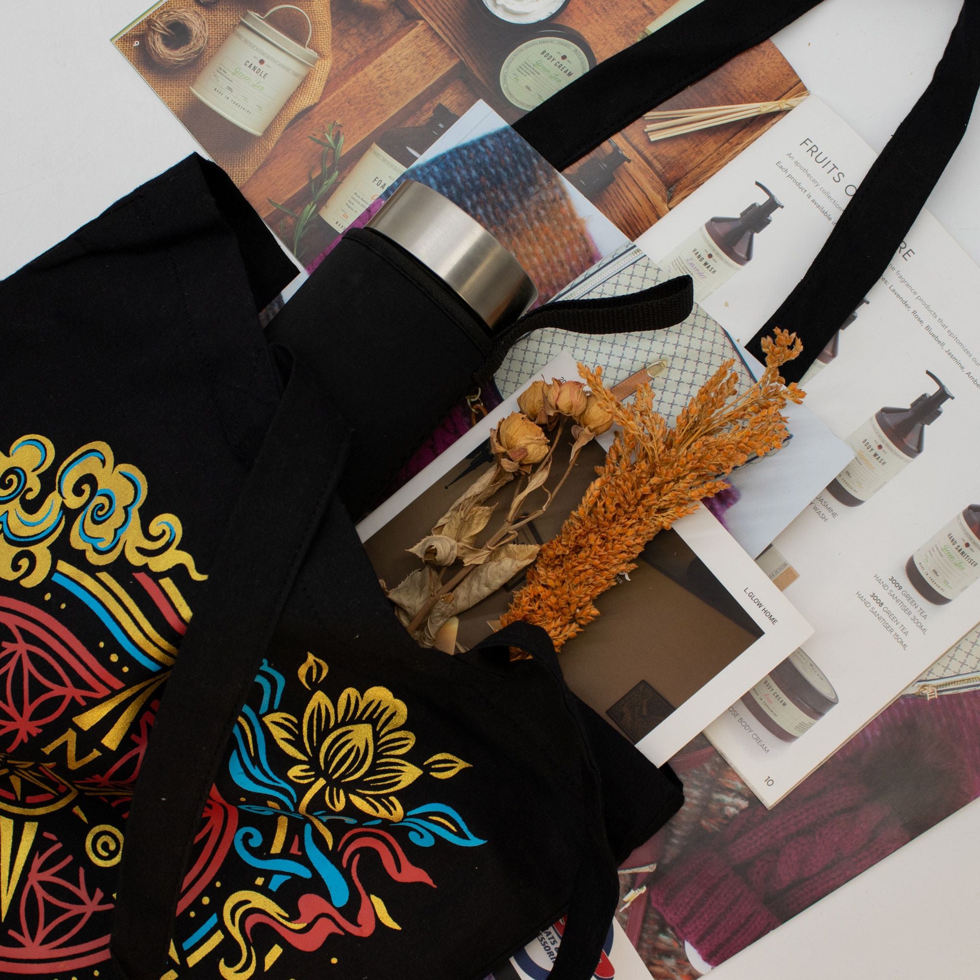 Black tote bag with colorful floral design on a magazine background