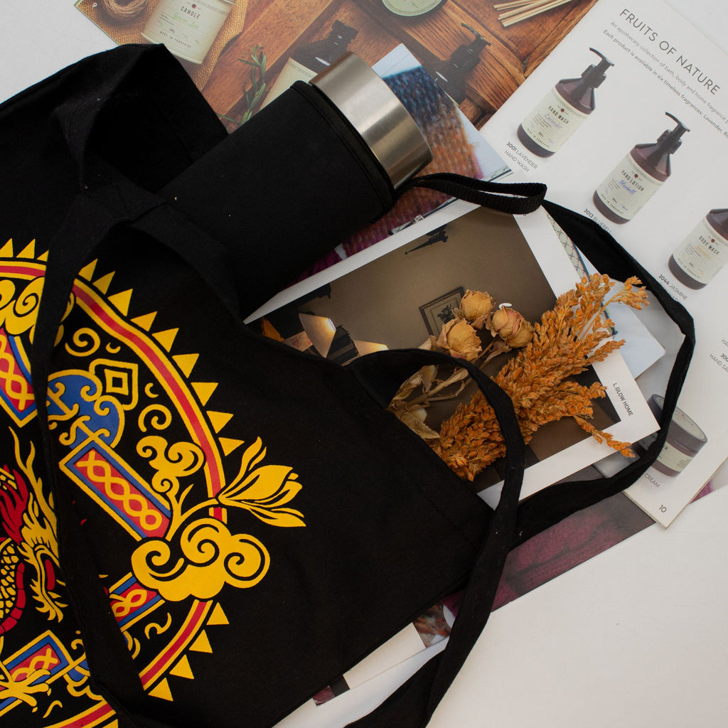 Black tote bag with colorful patterns on a magazine with beauty products.