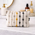 Decorative pouch with pom-pom details on a bathroom counter