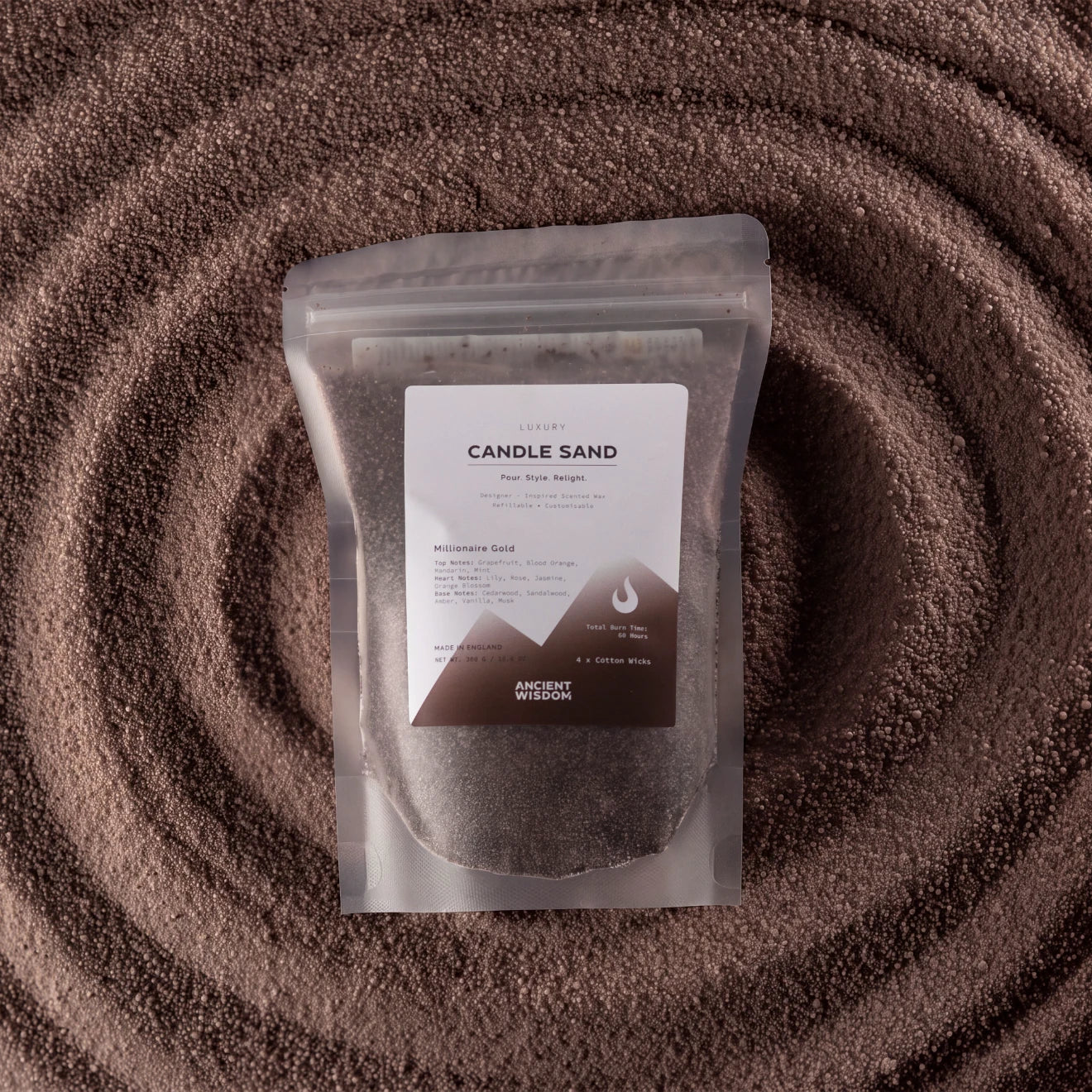 A stand-up pouch labeled 'Candle Sand' filled with dark brown wax, placed on a textured brown surface with concentric circular patterns.