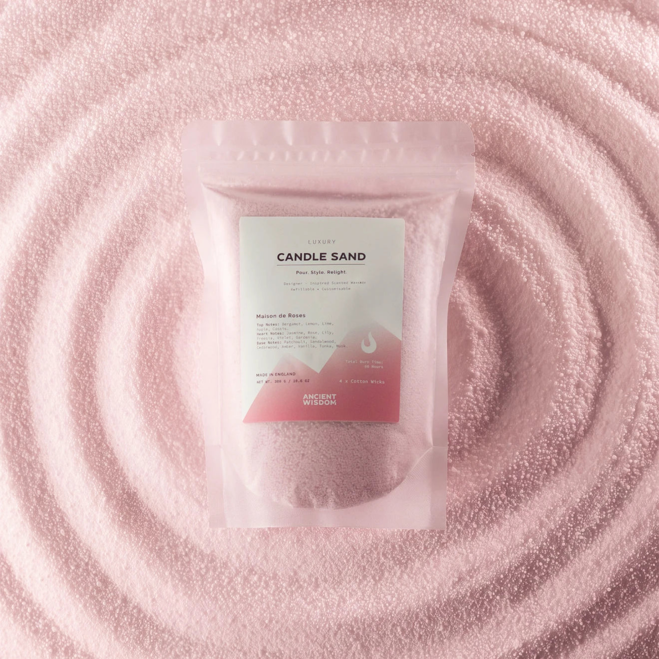 A stand-up pouch labeled 'CANDLE SAND' with a white and pink label, placed on a textured pink surface with concentric circular ripples behind it.