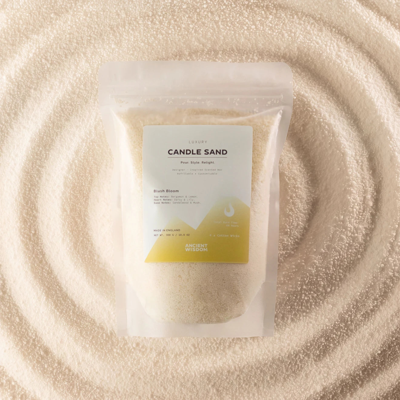 A stand-up pouch labeled 'CANDLE SAND' containing pale cream wax, placed on a textured surface of matching cream wax in a circular pattern. The label has a white top half and a yellow-green geometric bottom section.