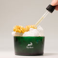 Hop Hare Diffusing Crystals & Floral Set - The Lion Green container with flowers and ice, dropper adding liquid, ' hop Hare' brand visible