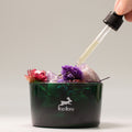 Lip balm container with flowers and a dropper adding liquid.