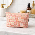 Pink patterned toiletry bag on a bathroom counter with skincare products.