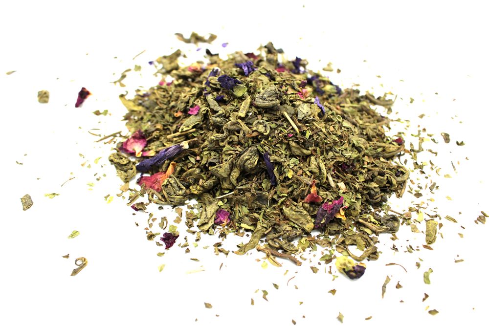 Heap of green tea leaves with small colorful flowers on a white background