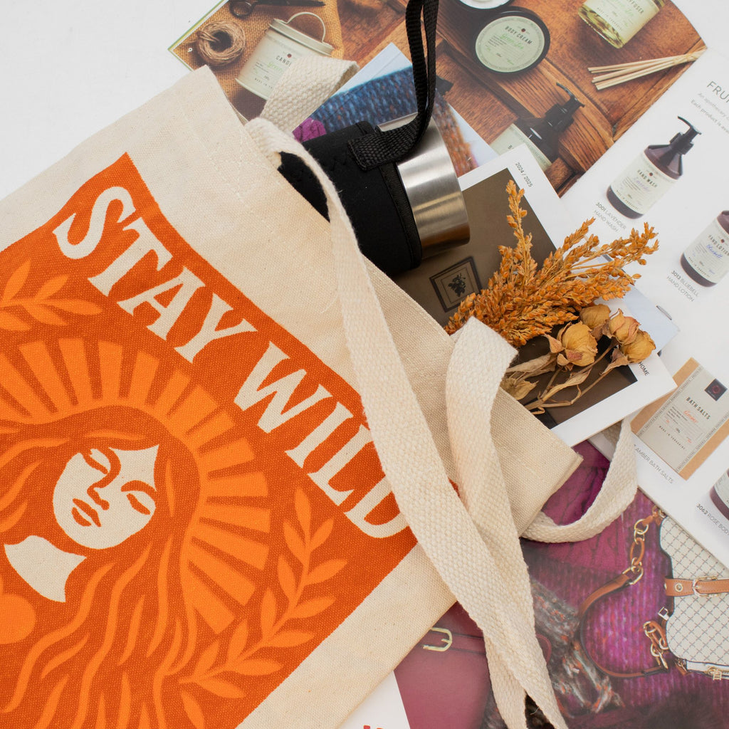 Starbucks tote bag with 'Stay Wild' text on a surface with various items.