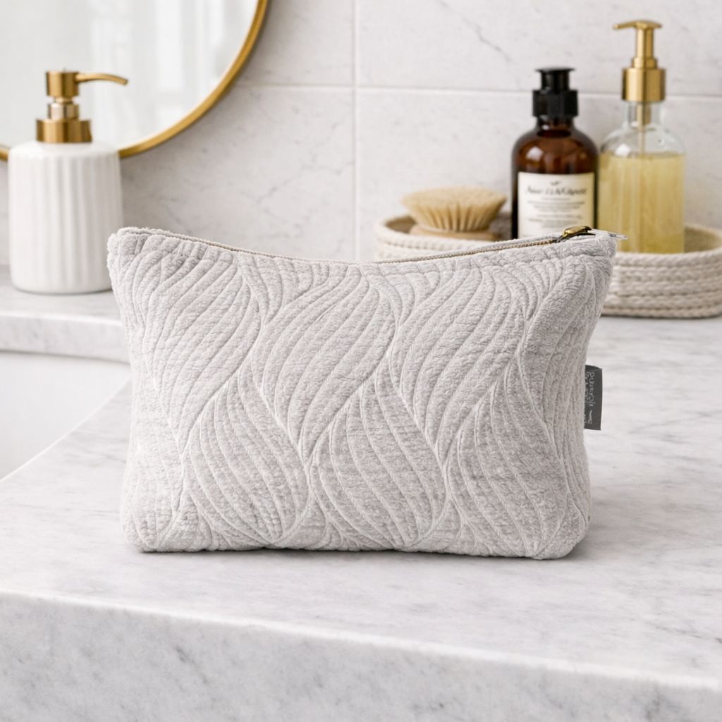 Textured gray pouch on a bathroom counter with various items in the background