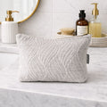 Textured gray pouch on a bathroom counter with various items in the background