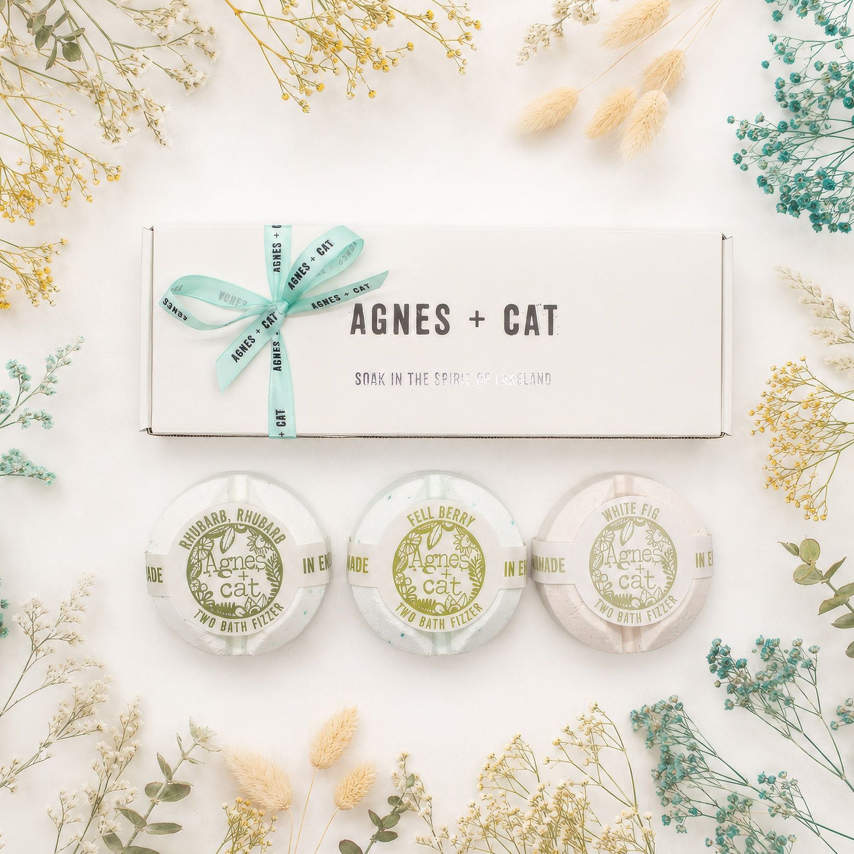 Three bath pillows with 'Agnes + Cat' branding on a white background with decorative plants.
