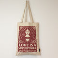 Tote bag with 'Love is a Superpower' design on a plain background